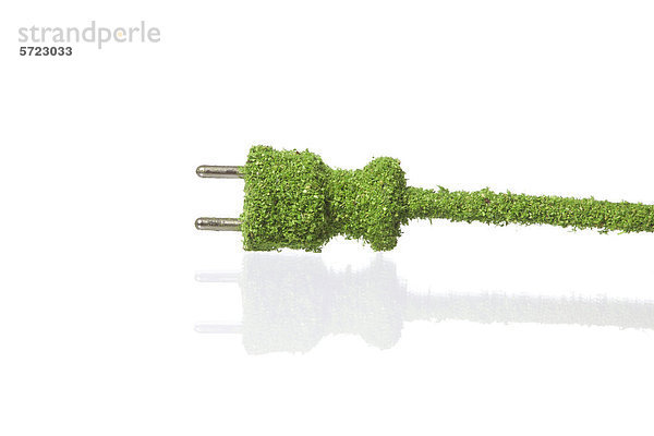 Elektrischer Stecker mit Gras bedeckt auf weißem Hintergrund