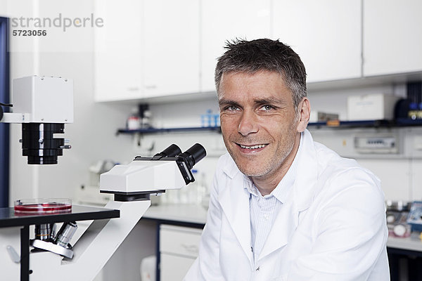 Deutschland  Bayern  München  Wissenschaftler mit Mikroskop im Labor  Portrait