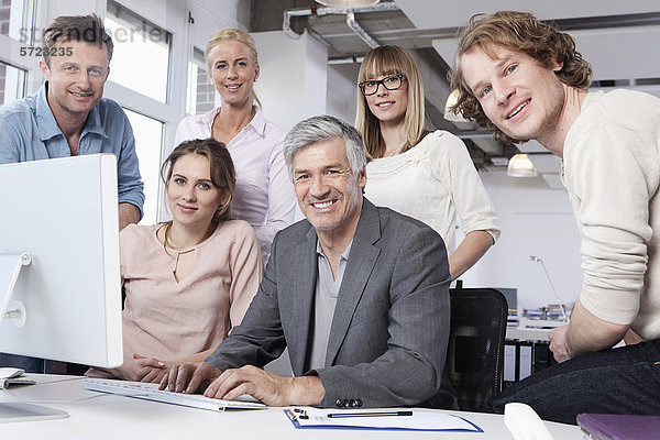 Männer und Frauen mit Computer im Büro  lächelnd  Porträt