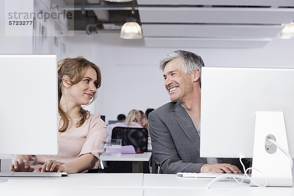 Mann und Frau mit Computer im Büro  lächelnd