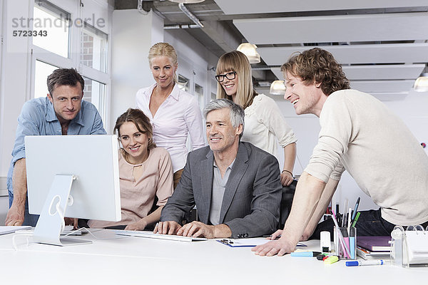 Männer und Frauen  die den Computer im Büro benutzen  lächelnd