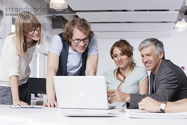 Männer und Frauen mit Laptop im Büro