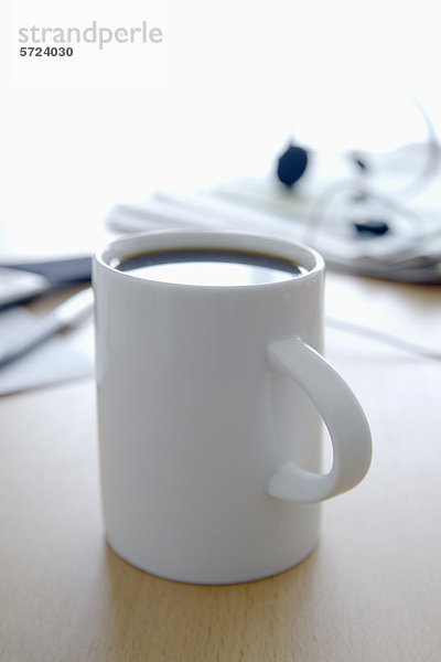 Tasse Kaffee  Zeitung  Handy  Stift und Kopf auf Bürotisch  Nahaufnahme
