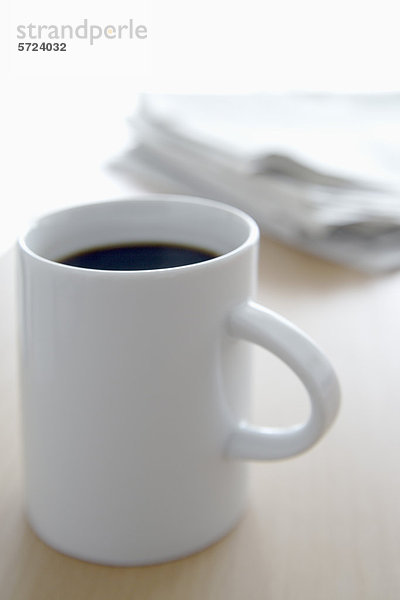 Tasse Kaffee und Zeitung auf dem Bürotisch  Nahaufnahme