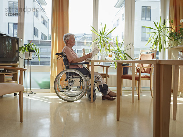 Seniorin beim Zeitungslesen im Pflegeheim