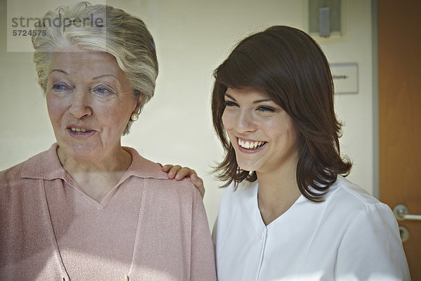 Seniorenfrauen und Betreuerinnen  die im Pflegeheim wegschauen  lächelnd