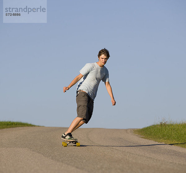 Österreich  Junger Mann beim Longboarding auf der Straße