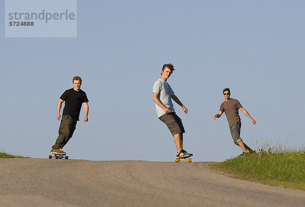 Österreich  Junge Männer beim Longboarding auf der Straße