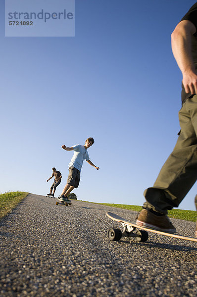 Österreich  Junge Männer beim Longboarding auf der Straße