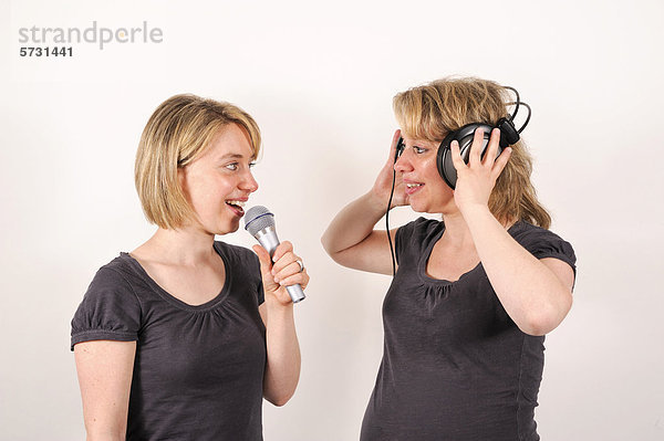 Zwillingsschwestern mit Mikrofon und Kopfhörer