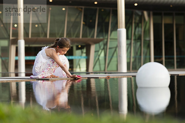 Mädchen platziert Blume auf der Wasseroberfläche