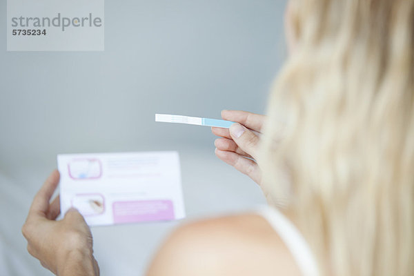 Frau liest Schwangerschaftstest  abgeschnitten