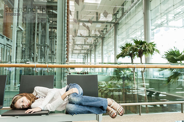 Mädchen auf Stühlen im Flughafen liegend