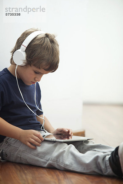 Junge mit Kopfhörer und Blick auf digitales Tablett