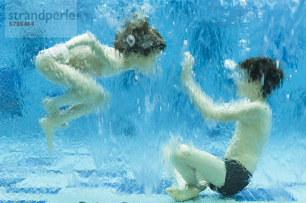 Geschwister spielen unter Wasser im Schwimmbad