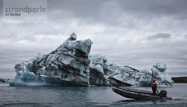 Motorboot fährt am Eisberg in der Jokulsarlon-Gletscherlagune vorbei  Island