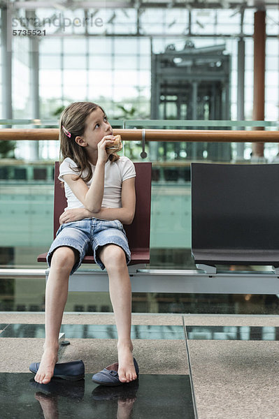 Mädchen sitzt im Flughafen und isst Sandwich  Porträt