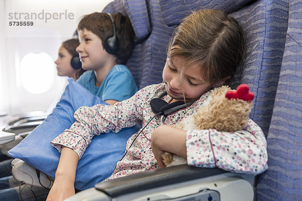 Mädchen schläft im Flugzeug mit Plüschtier