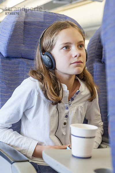 Mädchen sehen Film mit Kopfhörer im Flugzeug