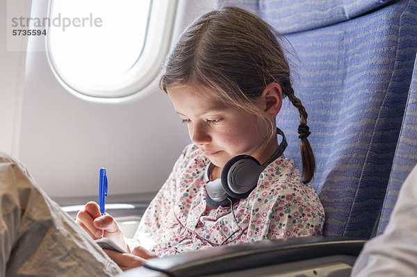 Mädchen schreiben im Notizbuch im Flugzeug