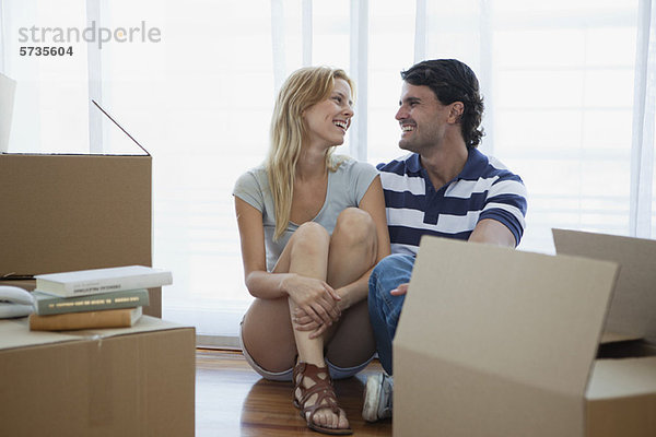 Paar auf dem Boden sitzend in neuem Haus mit Pappkartons