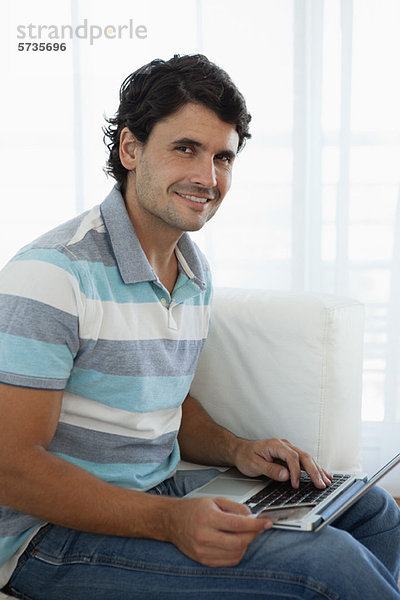 Mann mit Kreditkarte bei der Benutzung des Laptops  Portrait