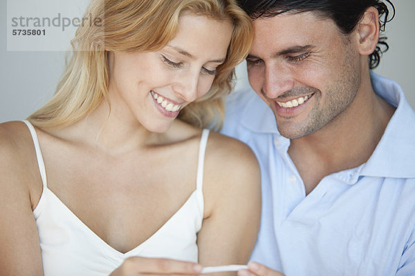 Paar schaut auf Schwangerschaftstest  lächelnd