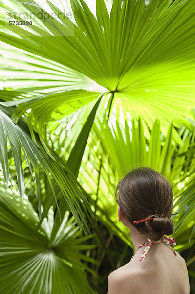 Mädchen beim Betrachten von Palmblättern  Rückansicht