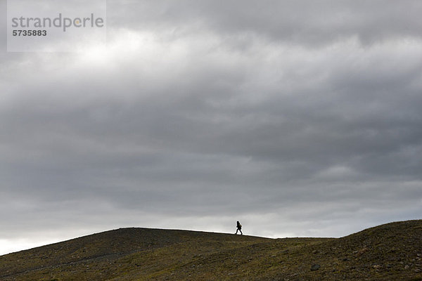Island  Person  die auf einem kargen Hügel spazieren geht.