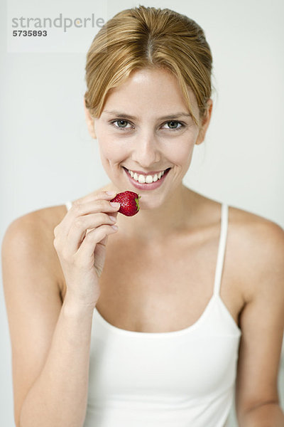 Junge Frau isst Erdbeere  Portrait