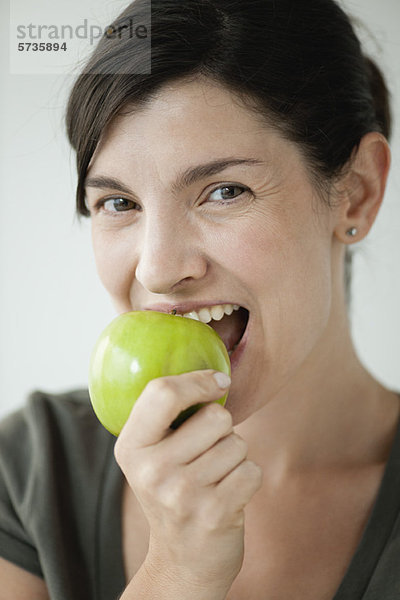 Frau im mittleren Erwachsenenalter beißt in den Apfel
