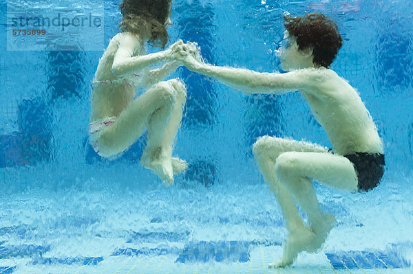 Geschwister spielen unter Wasser im Schwimmbad