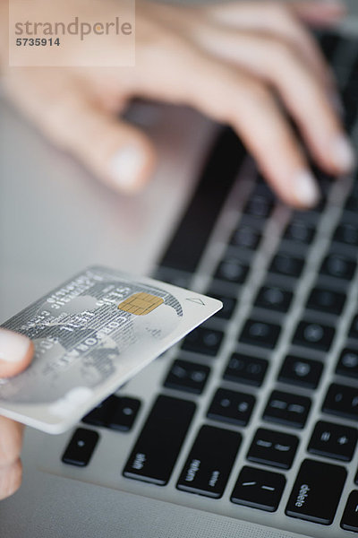 Frau mit Kreditkarte bei der Benutzung des Laptops  beschnitten