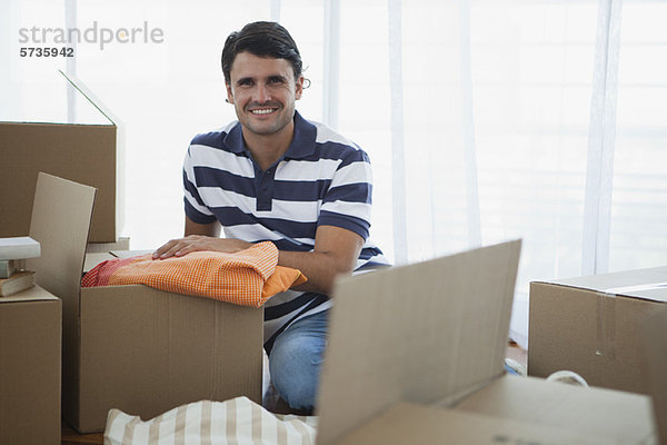 Mittlerer Erwachsener Mann beim Auspacken im neuen Haus