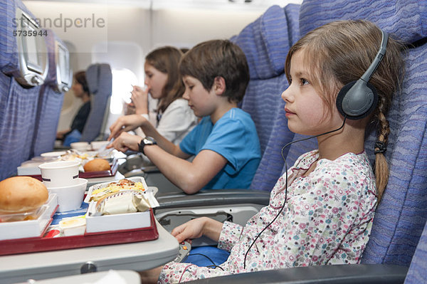 Mädchen sehen sich einen Film im Flugzeug an  Fluglinienessen auf dem Tablett.