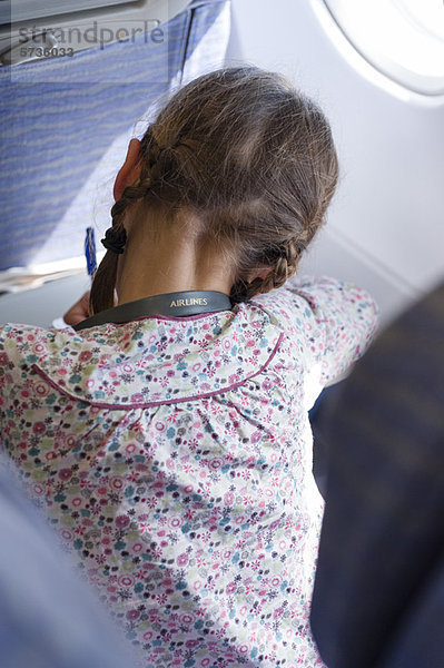Mädchen beim Schreiben im Flugzeug  Rückansicht