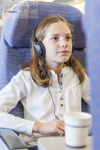 Mädchen sehen Film mit Kopfhörer im Flugzeug