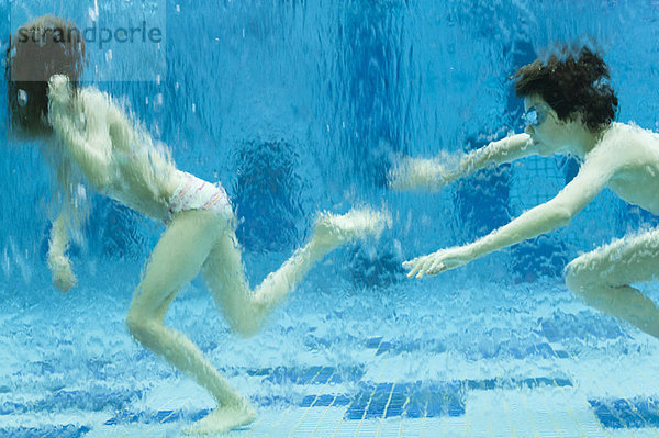 Geschwister wandern unter Wasser im Schwimmbad