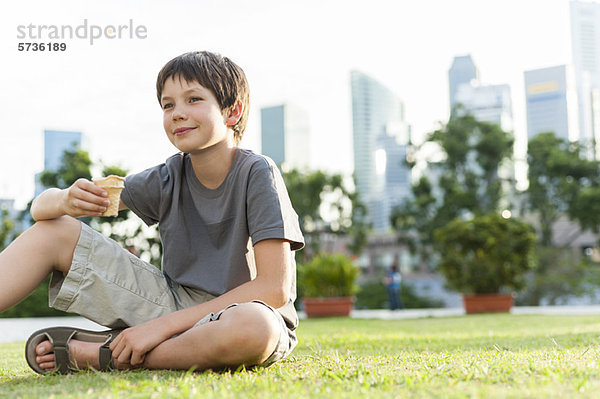 Junge sitzt auf Gras im Park  Stadtsilhouette im Hintergrund