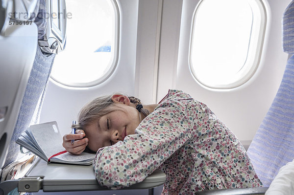 Mädchen ruhen Kopf auf Tablett-Tisch im Flugzeug