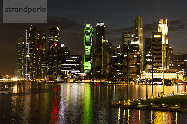 Singapur  Skyline am Wasser von der Promenade bei Nacht gesehen