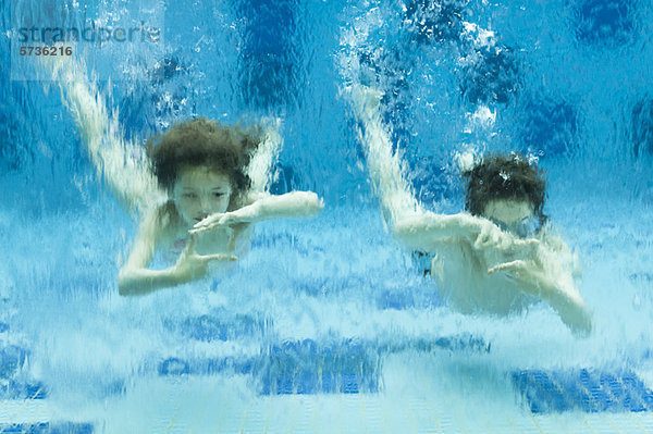Geschwister schwimmen unter Wasser im Schwimmbad  Hände bilden Fingerrahmen