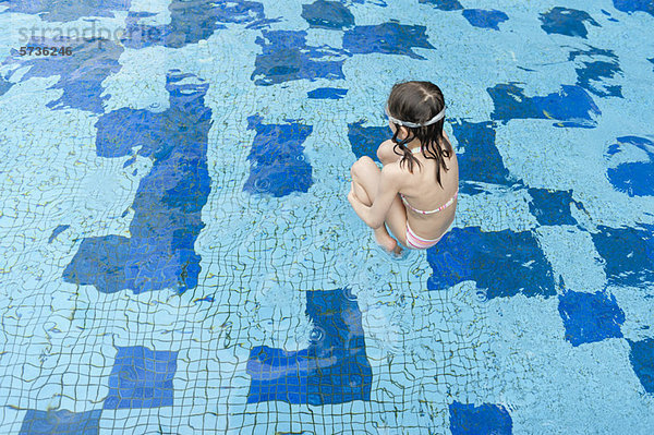 Mädchen springt ins Schwimmbad  Rückansicht