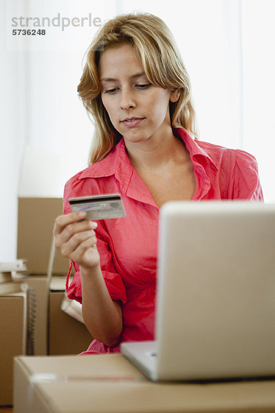 Junge Frau beim Online-Shopping für ihr neues Zuhause