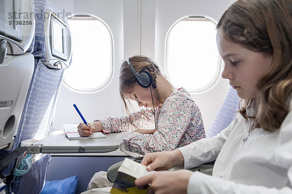 Mädchen beim Musikhören im Flugzeug mit Kopfhörer