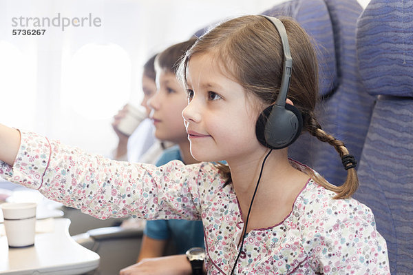 Mädchen sehen Film mit Kopfhörer im Flugzeug