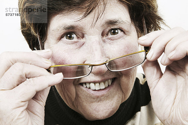 Seniorin schaut über Brillenrand  Porträt