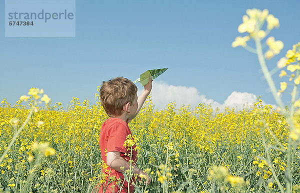 Junge spielt mit Papierflugzeug im Feld