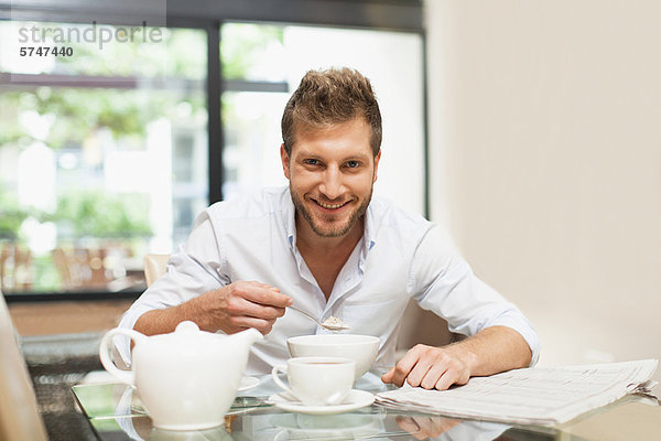 Lächelnder Mann beim Frühstücken am Tisch