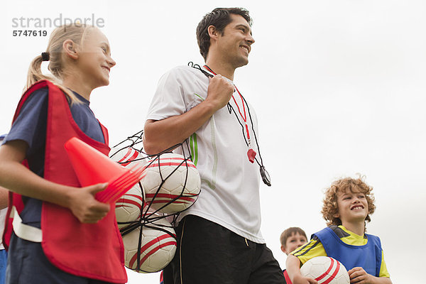 Trainer mit Fußbällen auf dem Spielfeld